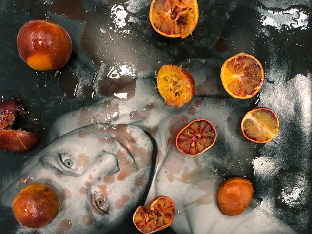 Mann im Wasser, blickt in die Kamera, mit Blutorangen bedeckt Mann im Wasser, blickt in die Kamera, mit Blutorangen bedeckt