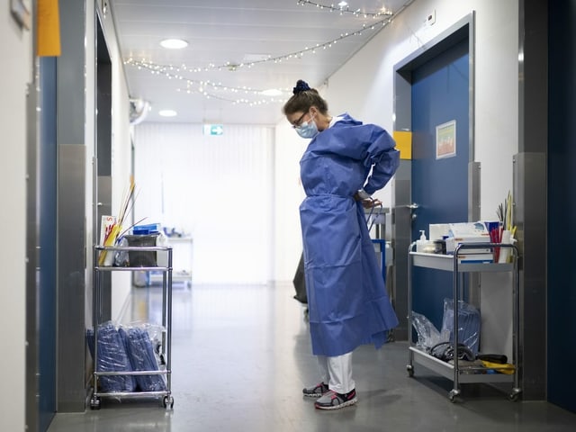 Eine Pflegefachfrau zieht ihre Schutzkleidung an. Eine Pflegefachfrau zieht ihre Schutzkleidung an.
