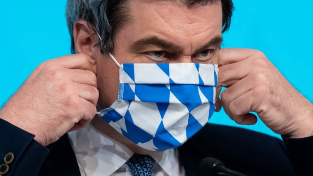 Markus Söder zieht sich eine Hygienemaske an Markus Söder zieht sich eine Hygienemaske an