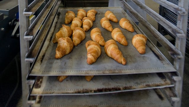 Firsch aufgebackene Gipfeli auf einem Backblech in einer Grossbäckerei. Firsch aufgebackene Gipfeli auf einem Backblech in einer Grossbäckerei.