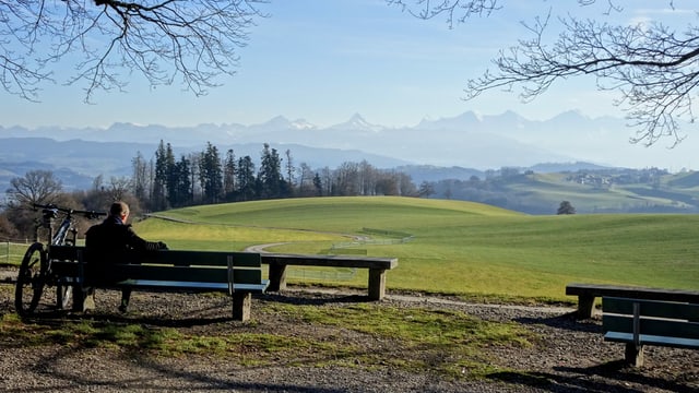 Radfahrer sitzt auf einer Parkbank auf dem Gurten und geniesst das warme Weihnachtwetter. Radfahrer sitzt auf einer Parkbank auf dem Gurten und geniesst das warme Weihnachtwetter.