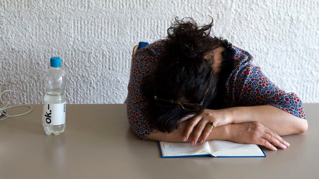 Frau sitzt an einem Tisch mit dem Kopf auf dem Tisch Frau sitzt an einem Tisch mit dem Kopf auf dem Tisch