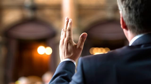 Parlamentarier von hinten. Seine Hand schneidet den Plenarsaal in zwei Hälften. Parlamentarier von hinten. Seine Hand schneidet den Plenarsaal in zwei Hälften.