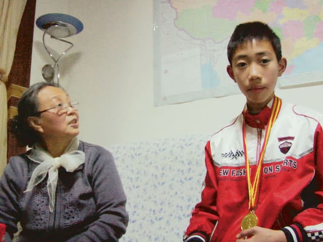Ein chinesischer Schüler mit Goldmedaille um den Hals, daneben seine Grossmutter. Ein chinesischer Schüler mit Goldmedaille um den Hals, daneben seine Grossmutter.