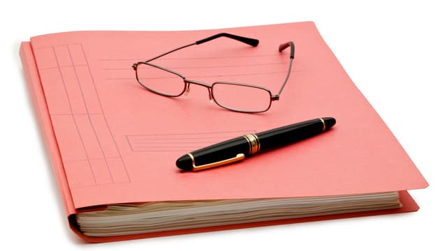 Ein kleiner Ordner, darauf eine Brille und ein Kugelschreiber. Ein kleiner Ordner, darauf eine Brille und ein Kugelschreiber.