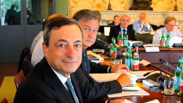 EZB-Präsident Mario Draghi lächelnd an einem Konferenztisch. EZB-Präsident Mario Draghi lächelnd an einem Konferenztisch.