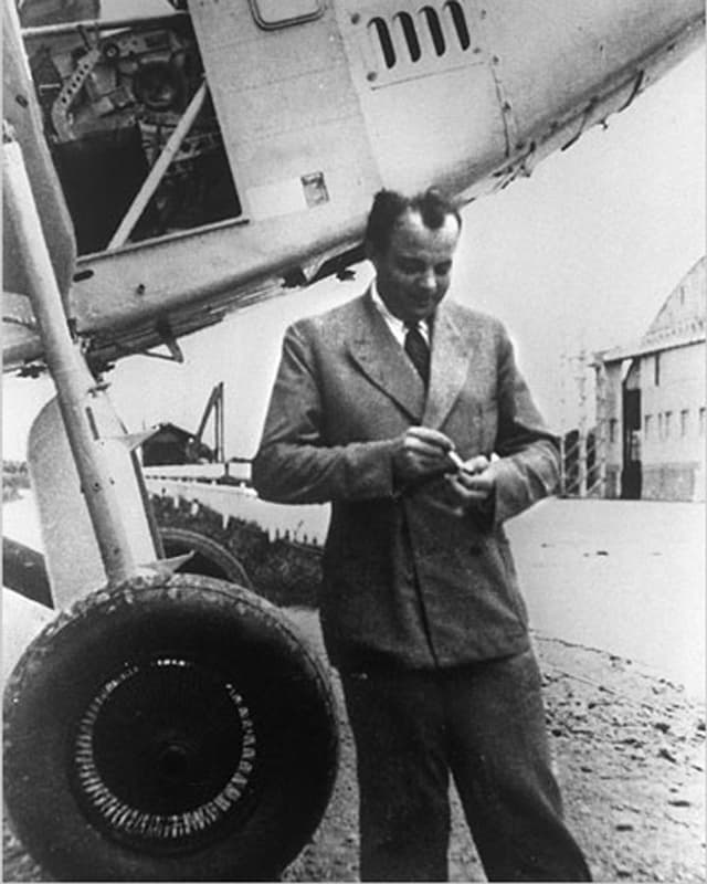 Schwarzweissbild: Saint-Exupéry im Anzug vor einem Flugzeug. Schwarzweissbild: Saint-Exupéry im Anzug vor einem Flugzeug.