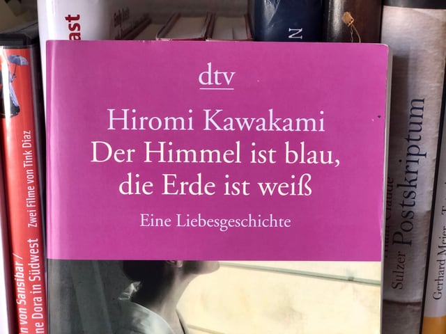 Hiromi Kawakami: «Der Himmel ist blau, die Erde ist weiss» auf einem Bücherregal stehend. Hiromi Kawakami: «Der Himmel ist blau, die Erde ist weiss» auf einem Bücherregal stehend.