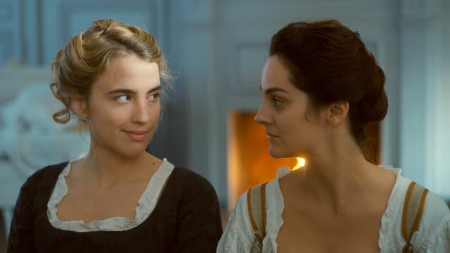 Zwei Frauen in historischen Kleidern lächeln sich an. Zwei Frauen in historischen Kleidern lächeln sich an.