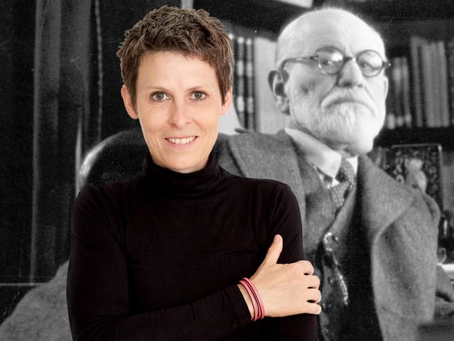 Ein Frau schaut in die Kamera, hinter ihr ist ein Portrait Sigmund Freuds zu erkennen. Ein Frau schaut in die Kamera, hinter ihr ist ein Portrait Sigmund Freuds zu erkennen.