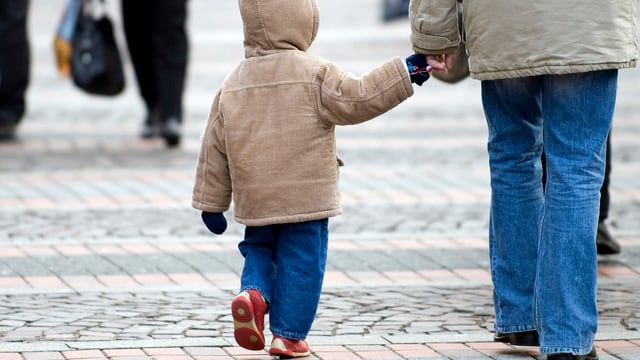 Eine Person hält ein Kind an der Hand. Eine Person hält ein Kind an der Hand.