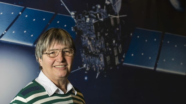 Frau mit Brille und kurzen grauen Haaren vor einem Satellit. Frau mit Brille und kurzen grauen Haaren vor einem Satellit.