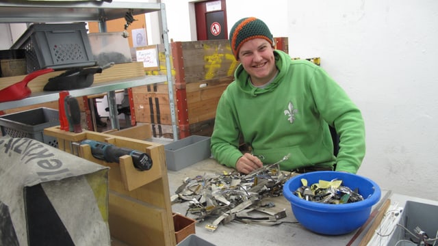 Ein junger sitzt in einer Werkstatt vor einem Haufen Metall. Ein junger sitzt in einer Werkstatt vor einem Haufen Metall.