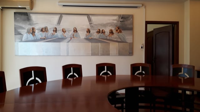 Ein Konferenztisch mit mehreren Stühlen, dahinter ein Bild des "letzten Abendmahls". Ein Konferenztisch mit mehreren Stühlen, dahinter ein Bild des "letzten Abendmahls".