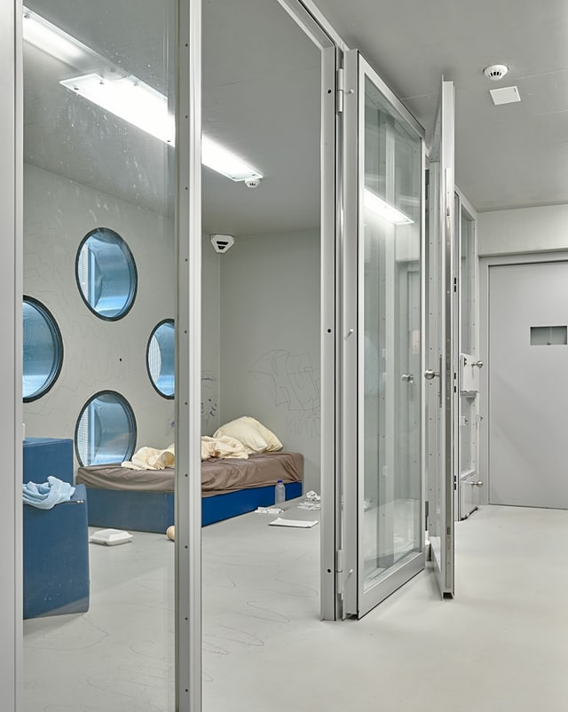 Eine Gefängniszelle hinter Glastüren. Eine Gefängniszelle hinter Glastüren.