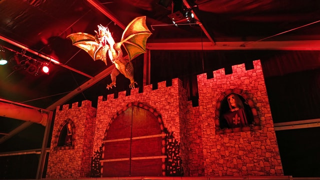 Bühnenbild aus Burg mit lebensechtem Drachen aus Pappmaché im Scheinwerferlicht Bühnenbild aus Burg mit lebensechtem Drachen aus Pappmaché im Scheinwerferlicht