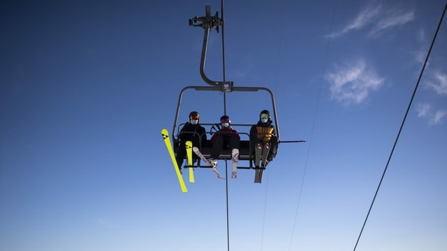 Menschen auf dem Skilift mit Maske