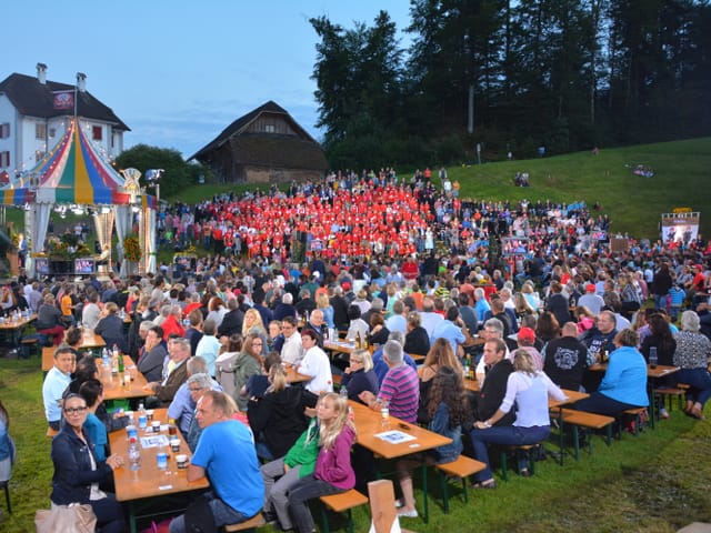 Voller Festplatz mit Festbänken und Jasszelt.