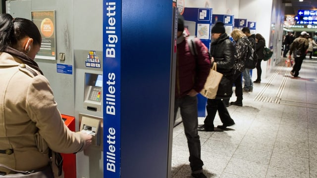 Eine Frau bezahlt ein Billett an einem Automat. Eine Frau bezahlt ein Billett an einem Automat.