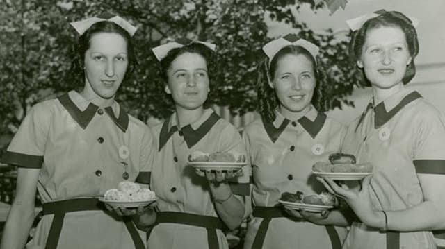Vier Frauen halten Teller mit Doughnuts in den Händen Vier Frauen halten Teller mit Doughnuts in den Händen