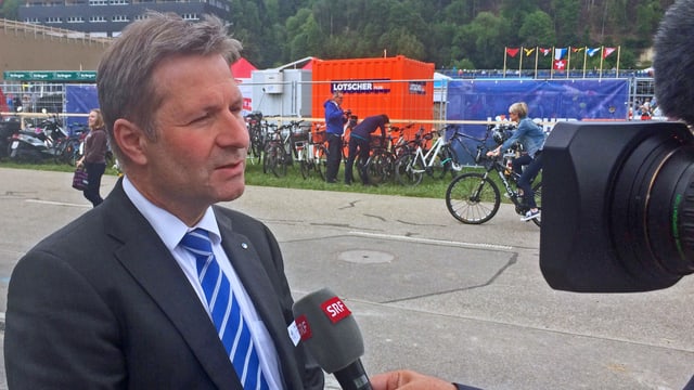 Ein Mann in Kravatte und Anzug vor einer Fernsehkamera. Ein Mann in Kravatte und Anzug vor einer Fernsehkamera.