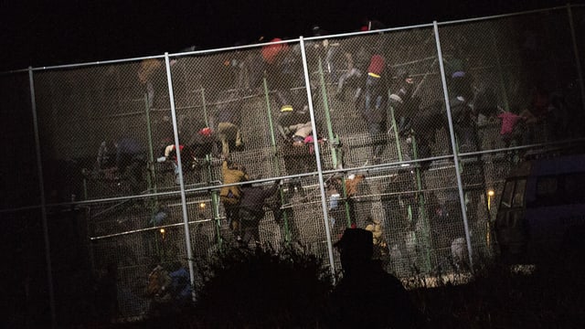 Migranten klettern über den Grenzzaun. Migranten klettern über den Grenzzaun.