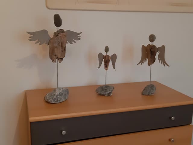 Selbstgebastelte Engel aus Metall und Holz auf einer Kommode.