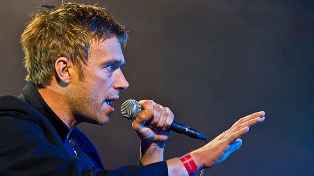 Damon Albarn auf der Bühne mit Mikrophon Damon Albarn auf der Bühne mit Mikrophon