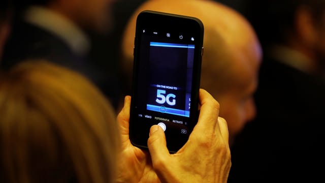 Eine Frau hält ein Smarphone in die Luft auf dem die Bezeichnung «5G» zu sehen ist. Eine Frau hält ein Smarphone in die Luft auf dem die Bezeichnung «5G» zu sehen ist.
