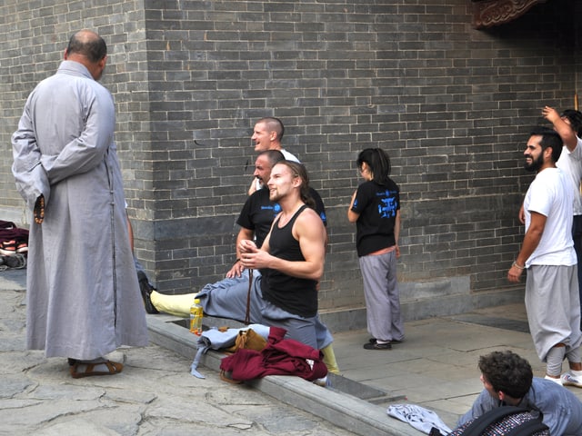 Menschen in Trainingskleidung im Gespräch mit einem Mönch.