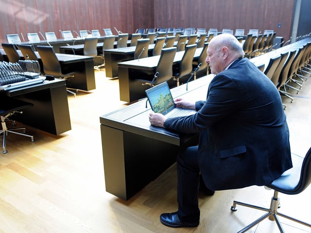 Giezendanner am Laptop in einem grossen Konferenzraum.