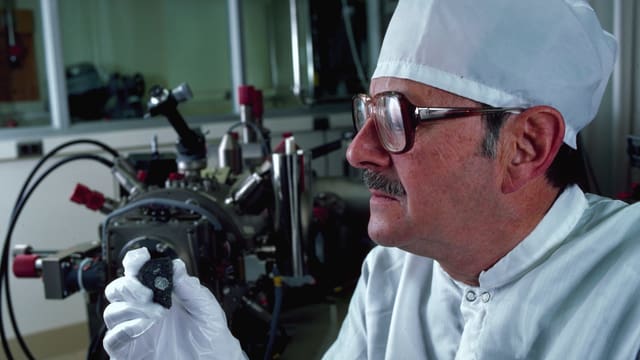 Ein Forscher schaut ein Stück des Meteroiten genau an. Ein Forscher schaut ein Stück des Meteroiten genau an.