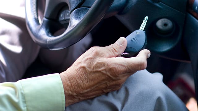 Hand einer alten Person hält Autoschlüssel Hand einer alten Person hält Autoschlüssel