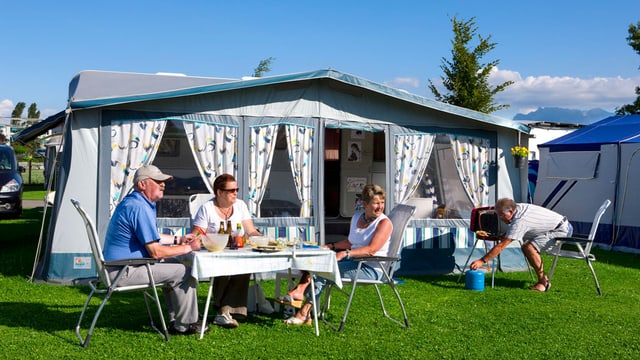 Camper sitzen am gedeckten Tisch vor einem Vorzelt. Camper sitzen am gedeckten Tisch vor einem Vorzelt.