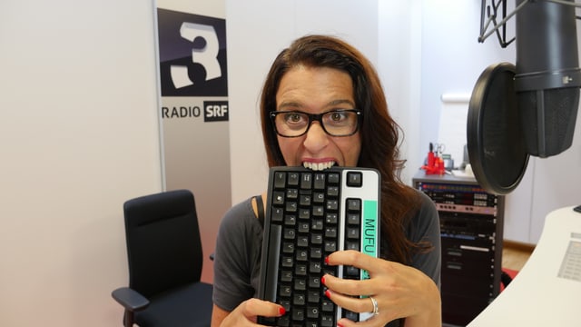 Rahel Giger im SRF 3 Studio; sie beisst in eine Computer-Tastatur. Rahel Giger im SRF 3 Studio; sie beisst in eine Computer-Tastatur.