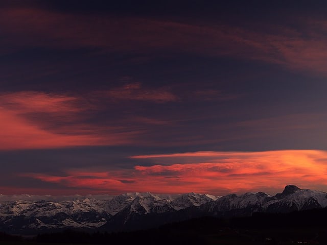 Schneeberge und blauviolett leuchtender Himmel, rosa Wolken.
