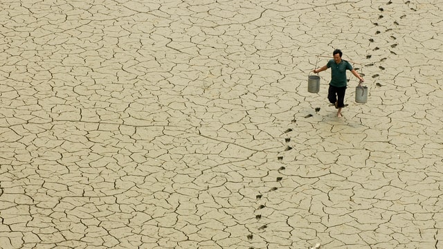 Chinesischer Bauer schleppt Kübel mit Wasser über ausgedörrte Erde. Chinesischer Bauer schleppt Kübel mit Wasser über ausgedörrte Erde.