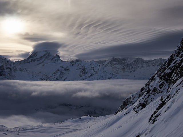 Verschiedene Wolkenschichten vor und über den Bergen.