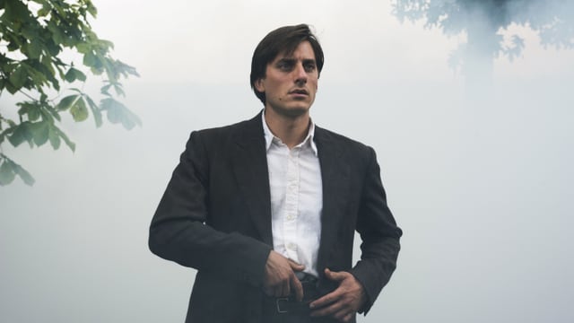 Ein junger Mann steht im Nebel, die Hand an einer Pistole, die in seinem Hosenbund steckt. Ein junger Mann steht im Nebel, die Hand an einer Pistole, die in seinem Hosenbund steckt.