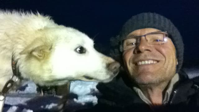 Ein Hund schnüffelt an einem Mann mit Mütze. Ein Hund schnüffelt an einem Mann mit Mütze.