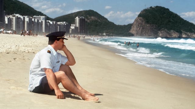 Mann in Piloten-Uniform sitzt am Strand. Mann in Piloten-Uniform sitzt am Strand.