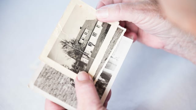 Eine Hand zeigt auf ein altes Foto Eine Hand zeigt auf ein altes Foto