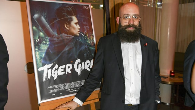 Der Regisseur Jakob Lass steht vor dem Filmplakat von "Tiger Girl". Der Regisseur Jakob Lass steht vor dem Filmplakat von "Tiger Girl".