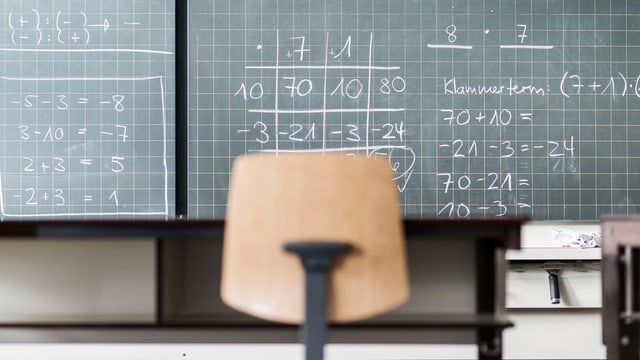 In einem Schulzimmer steht ein Stuhl vor einer Wandtafel. In einem Schulzimmer steht ein Stuhl vor einer Wandtafel.