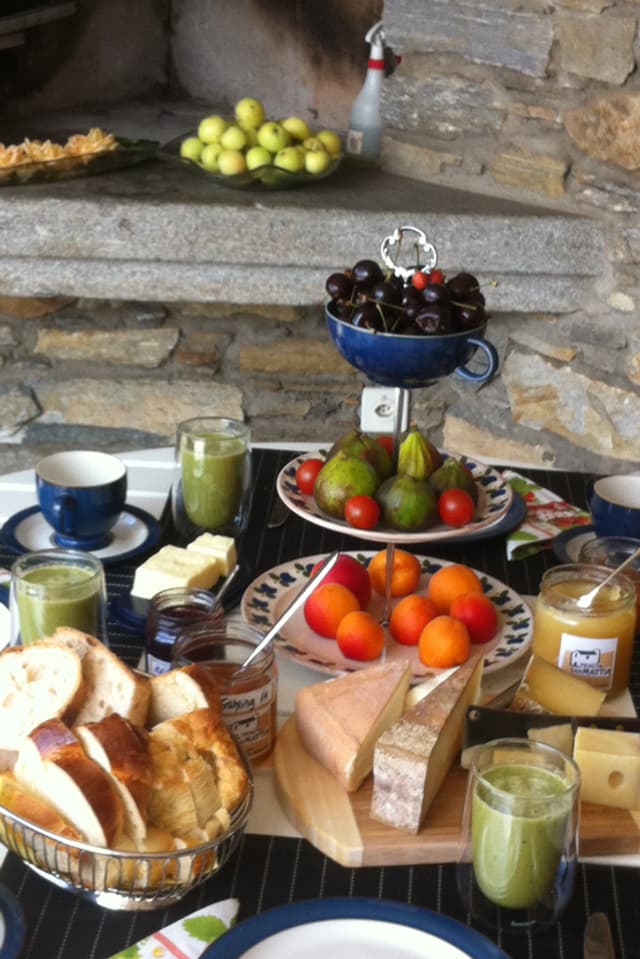 Tisch mit Zopf, Aprikosen, Käse, Tomaten, Honig, Saft.