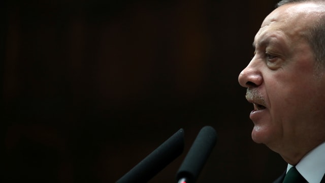 Erdogan spricht vor schwarzem Hintergrund in ein Mikrofon. Erdogan spricht vor schwarzem Hintergrund in ein Mikrofon.