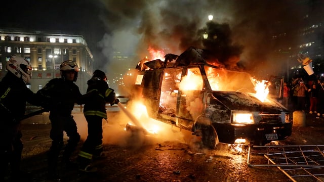 Die Feuerwehr versucht in der Nacht, ein brennendes Auto zu löschen. Die Feuerwehr versucht in der Nacht, ein brennendes Auto zu löschen.
