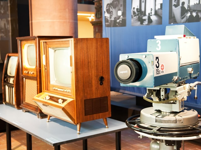 Drei alte Fernsehapparate, die in Holz gekleidet sind, und eine Kamera. Drei alte Fernsehapparate, die in Holz gekleidet sind, und eine Kamera.