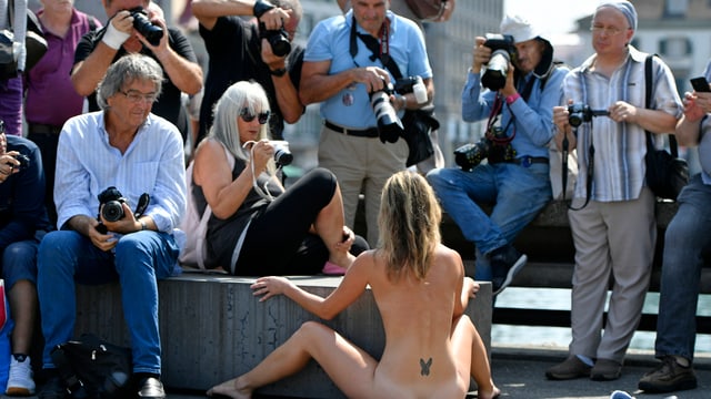 Eine Nacktkünstlerin performt in der Zürcher Innenstadt beobachtet von fotografierenden Männern Eine Nacktkünstlerin performt in der Zürcher Innenstadt beobachtet von fotografierenden Männern