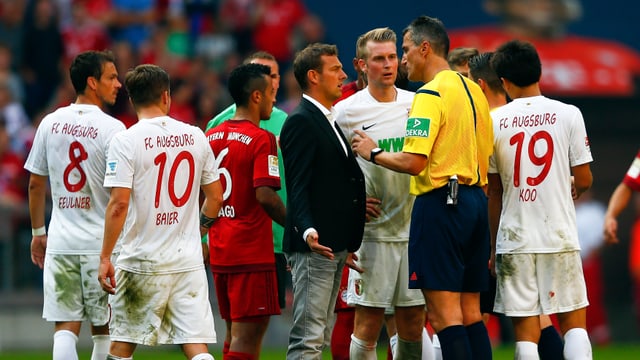 Augsburg-Spieler und ihr Trainer Markus Weinzierl diskutieren mit Schiedsrichter Knut Kircher. Augsburg-Spieler und ihr Trainer Markus Weinzierl diskutieren mit Schiedsrichter Knut Kircher.